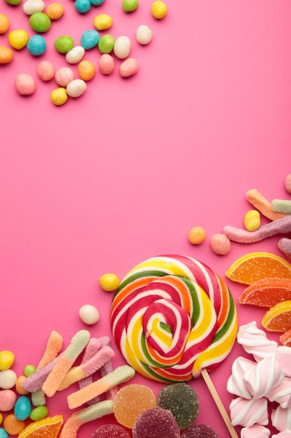 Colorful candies lollipops and jelly on pink background. Top view. Sweets background