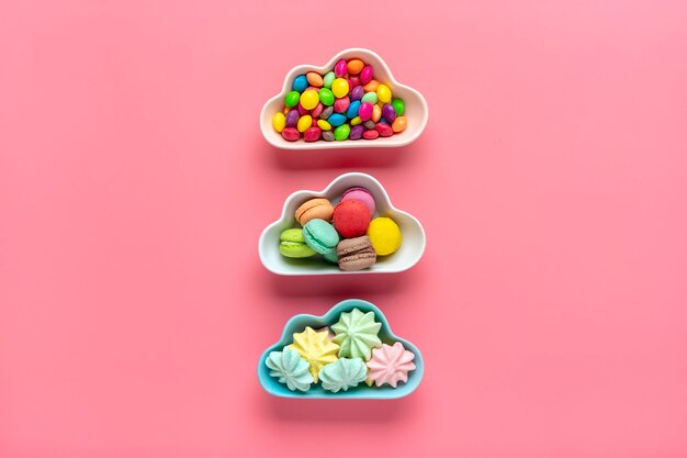 colorful candies - lollipops, meringues, macaroon in bowl in shape of cloud isolated on pink