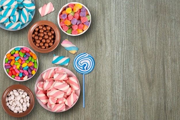 colorful candies marshmellows chocolate balls in jars lollipops and sweet peanuts and copy space