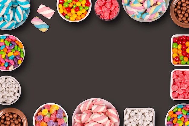 Colorful candies marshmellows chocolate balls in jars lollipops and sweet peanuts and copy space