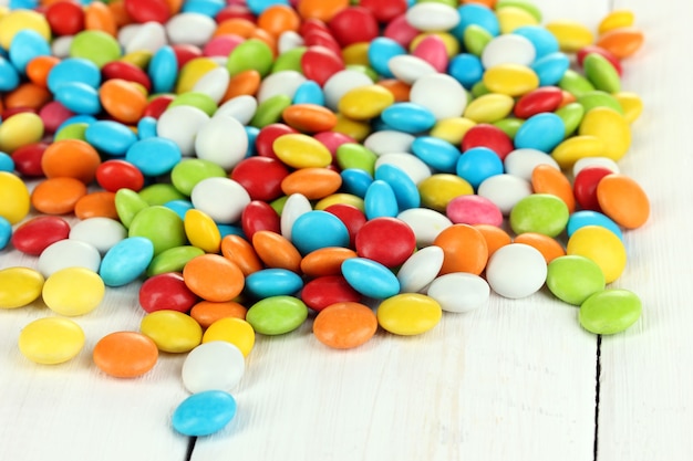 Colorful candies on white wooden background