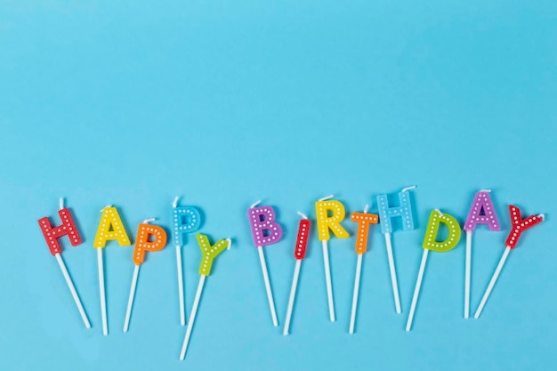 Colorful candles in letters with Happy Birthday lettering isolated on blue background