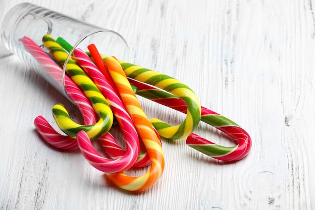 Colorful candy canes in glass on wooden background