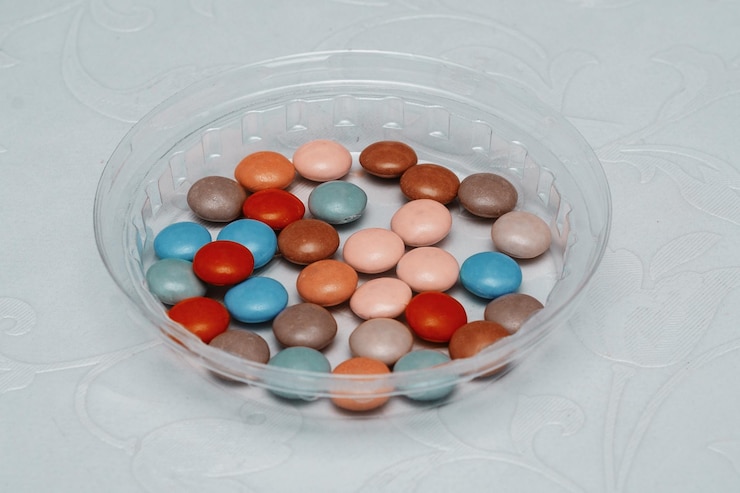 Photo colorful candy in a plastic cup on the table
