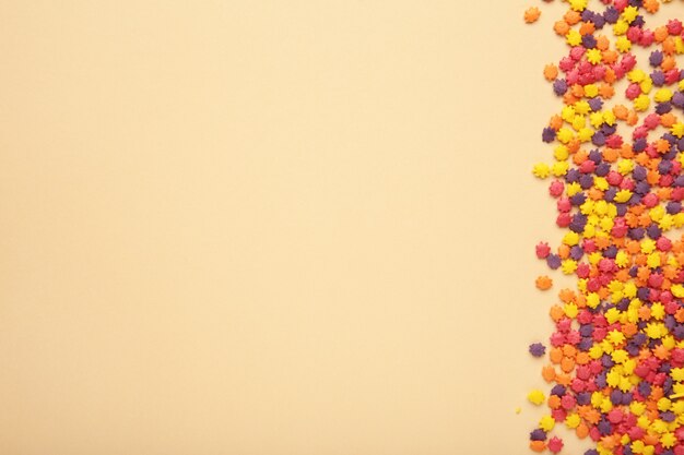 Colorful candy sprinkles on beige background