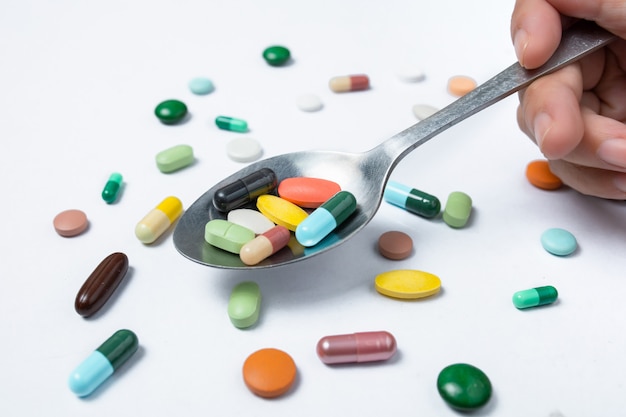 Colorful capsules and pills on spoon. health