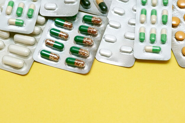 Colorful capsules with antibiotics in a blister pack on a yellow background Top view