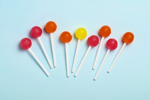 Colorful caramel on a stick. Blue background.Top view.