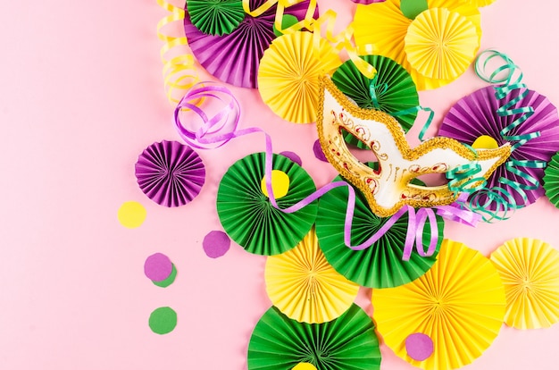 Colorful carnival fans and mask on pink table