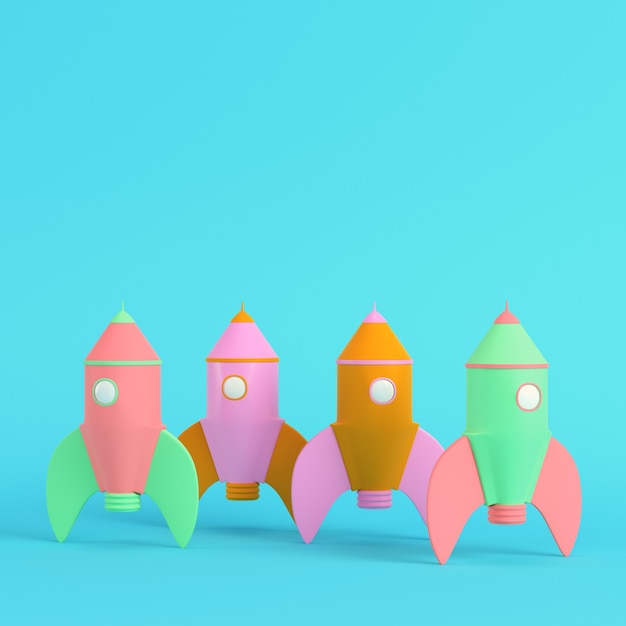 Colorful cartoon styled rockets on bright blue background in pastel colors. Minimalism concept. 3d render