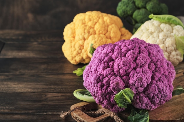 Colorful cauliflower Various sort of cauliflower on old wooden background Purple yellow white and green color cabbages Broccoli and Romanesco Agricultural harvest Mock up