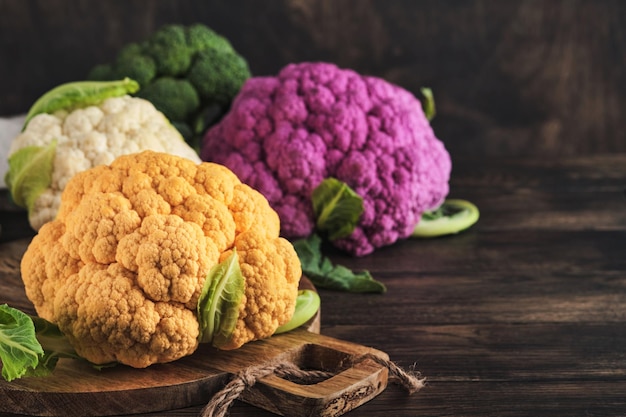 Colorful cauliflower Various sort of cauliflower on old wooden background Purple yellow white and green color cabbages Broccoli and Romanesco Agricultural harvest Mock up