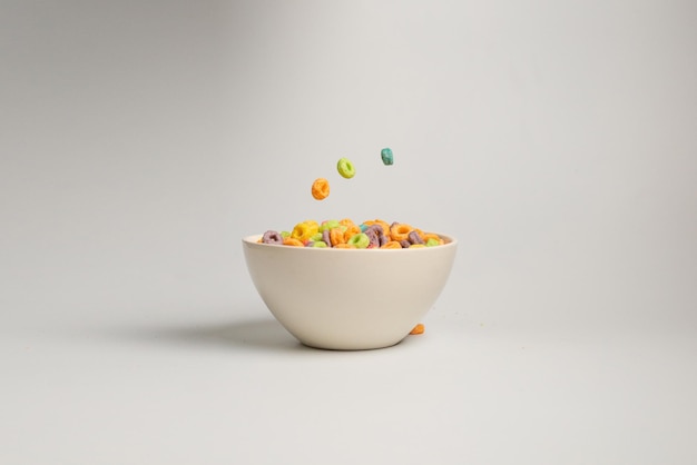 Photo colorful cereal box for morning breakfast corn flakes falling to the white bowl motion