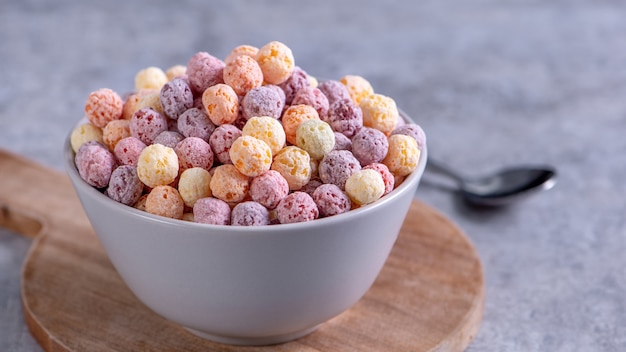 Mix di palline di mais di cereali colorate, dolci di ciotola di sapore di frutta su sfondo di cemento grigio, primo piano, colazione fresca, deliziosa e sana, concetto di design dello spazio della copia.