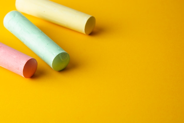 Colorful chalks over yellow background with copy space.