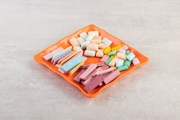 Colorful chewing gums placed on a stone table .