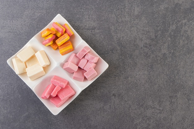 Colorful chewing gums placed on a stone table .