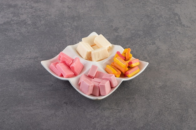 Colorful chewing gums placed on a stone table .