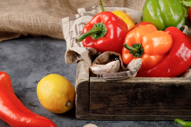 Colorful chilies with yellow lemon on wooden tray.