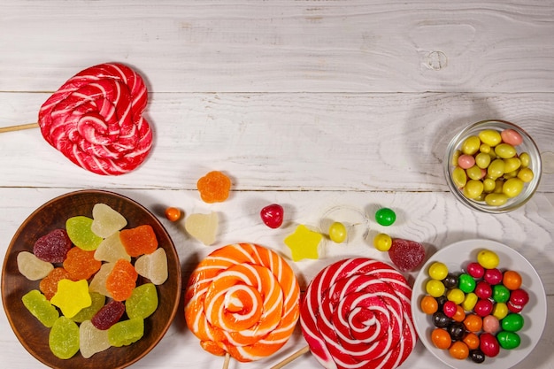 흰색 나무 테이블에 다채로운 초콜릿 사탕, 막대 사탕, 젤리 과자