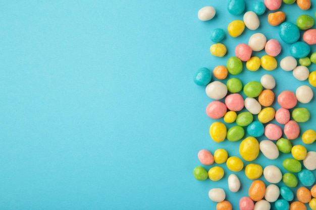 Colorful chocolate candy pills withs space on blue background. Top view