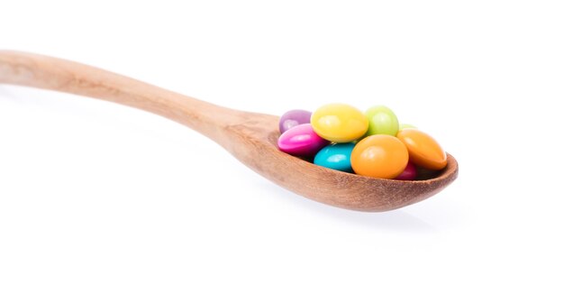colorful chocolate coated candy on spoon isolated on white background