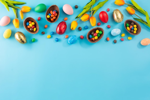 Colorful chocolate Easter eggs on blue bckground Top view Copy space