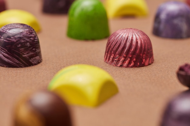 Colorful chocolates candies background isolated on brown.