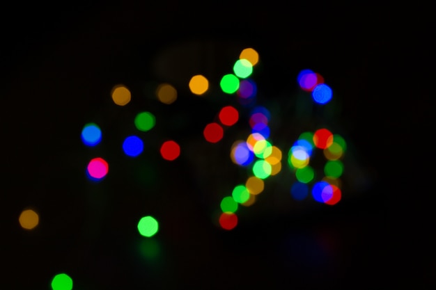 Foto bokeh variopinto di natale isolato su fondo nero. sfondo chiaro albero di natale. ne