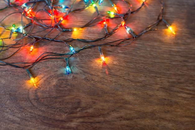 Colorful christmas lights over dark wooden background