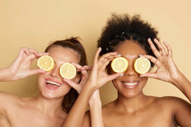 Photo colorful citrus circles near the face of cheerful multiracial women smiling