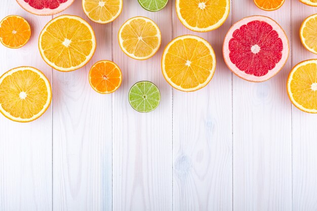 Colorful citrus fruits on white wooden background