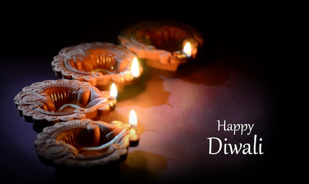 Colorful clay Diya lamps lit during Diwali celebration. Greetings Card Design Indian Hindu Light Festival called Diwali.