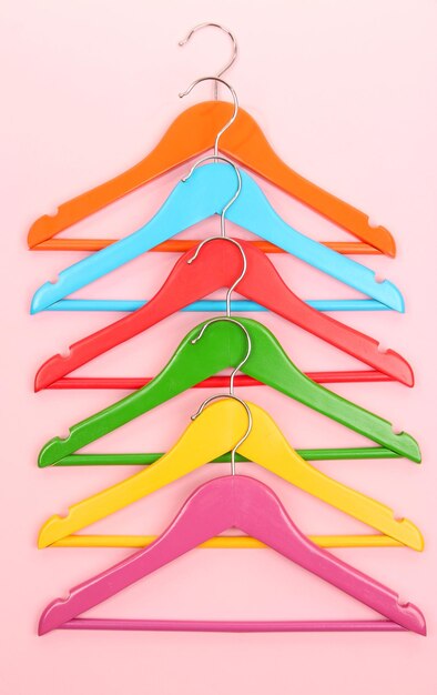 Colorful clothes hangers on pink background