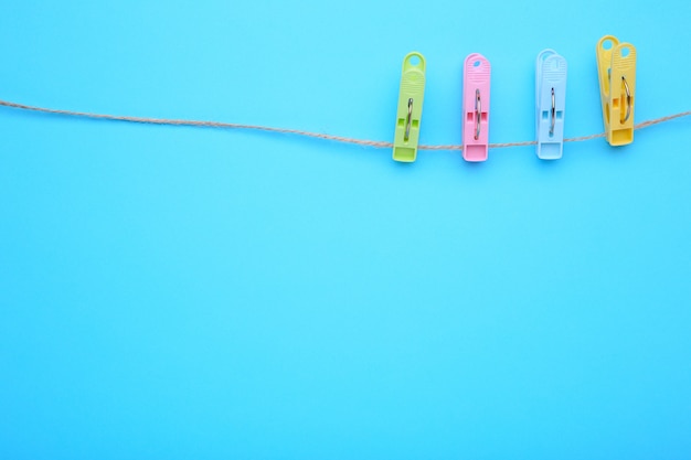 Colorful clothes pins on rope on blue