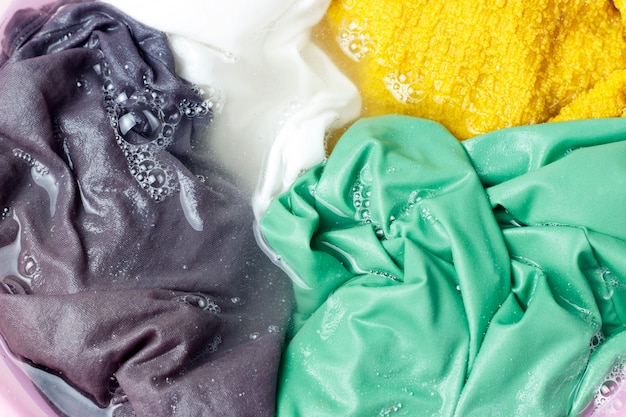 Фото Разноцветная одежда стирается тазом с мыльными пузырями