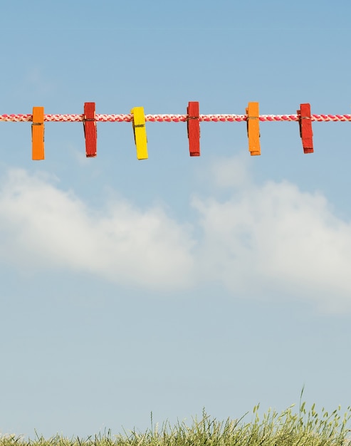 Colorful clothespins on a clothesline against the sky and grass