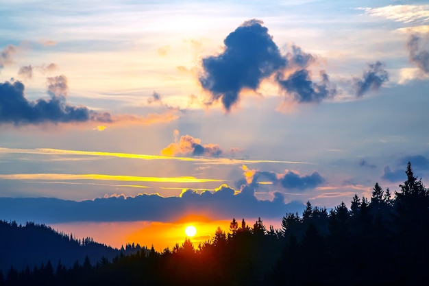 Colorful clouds in the sky at sunset against the backdrop of a mountainous forest area