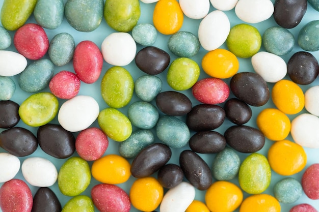 Colorful coated chocolate candies scattered on blue background