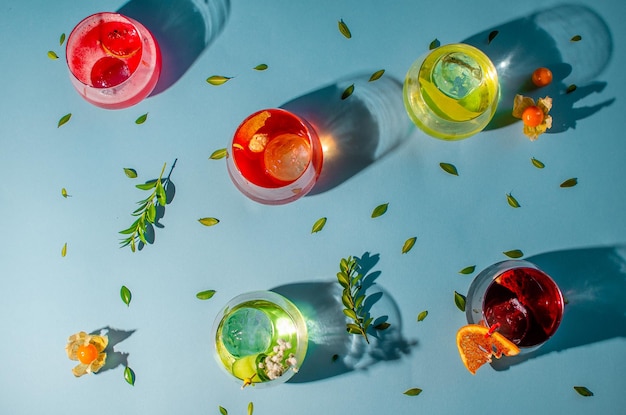 Foto cocktail colorati su sfondo blu con foglie verdi e un bicchiere di succo d'arancia.