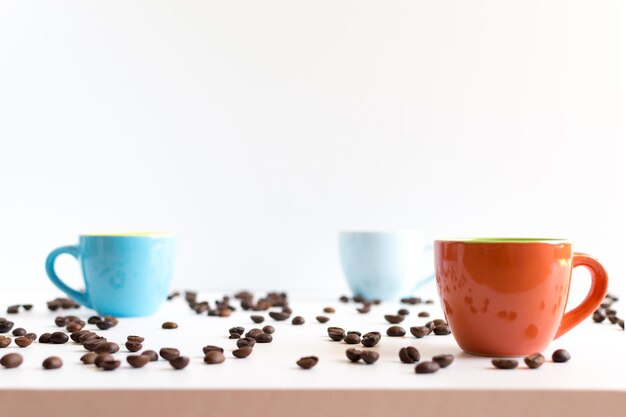 Красочные кофейные чашки на белом столе с фасолью
