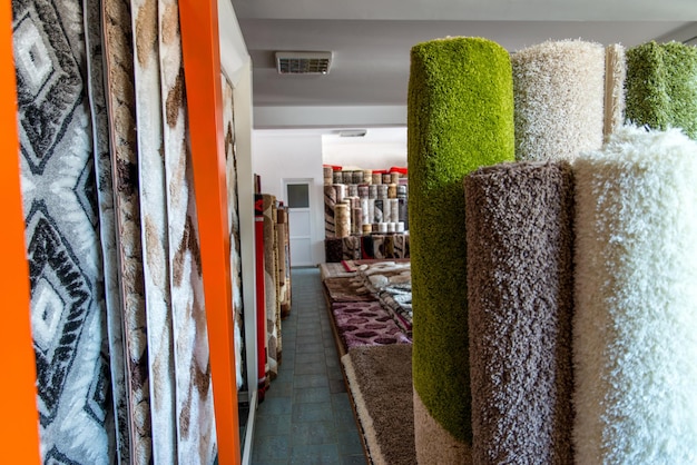 Фото Красочная коллекция ковров и ковриков, сложенных и выставленных на обозрение текстурированной поверхности ковра.