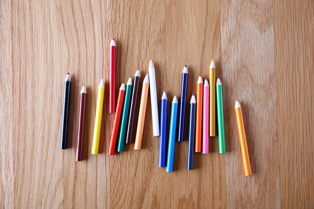 Colorful colored pencils lined up irregularly on the wooden desk