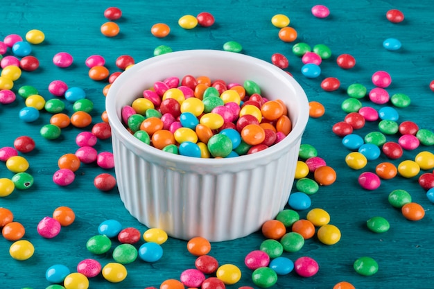 Colorful Confetti candy in bowl with blue surface.