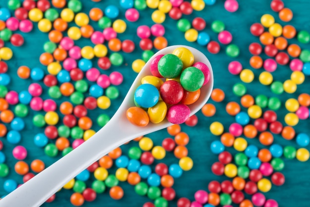 Photo colorful confetti candy in spoon top view.