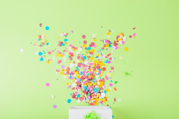 Photo colorful confetti falling in the white box over the green backdrop