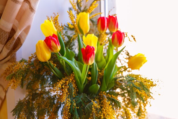 Colorful congratulatory spring bouquet of tulips and Mimosa. Small focus selected.