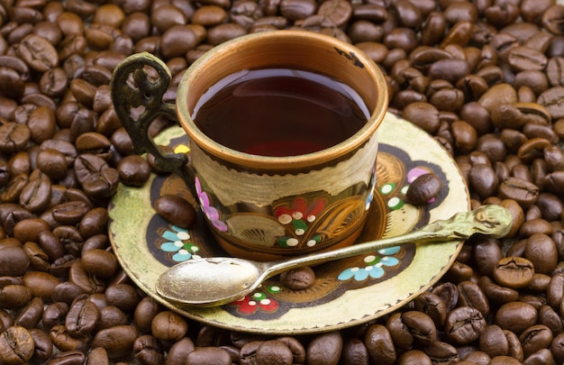 Colorful copper cup of coffee on a pile of coffee beans.