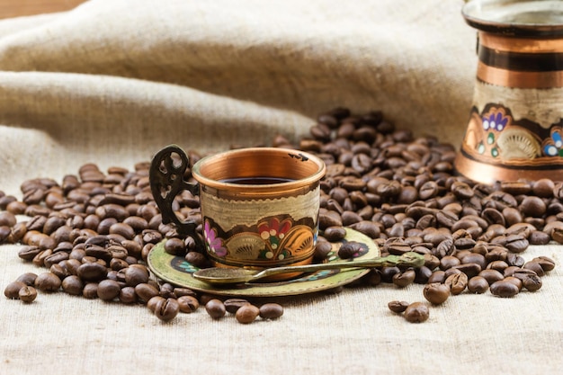 Colorful copper cup with scattered coffee beans