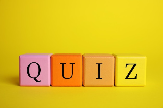 Colorful cubes with word Quiz on yellow background Space for text